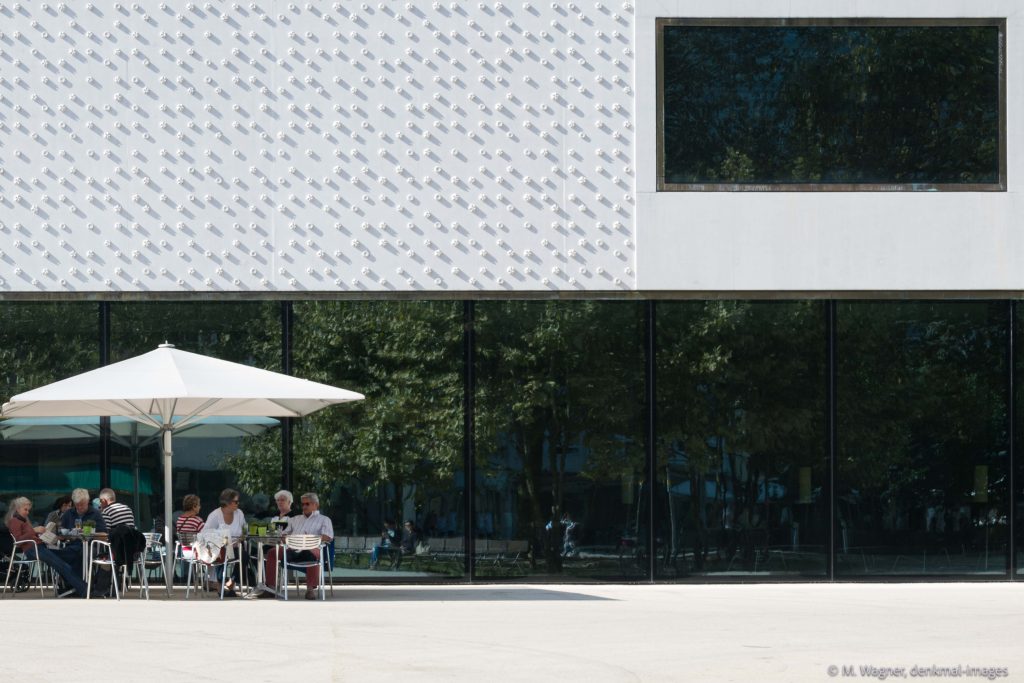 Eingang Vorarlberg Museum mit grossflächiger Verglasung und seitlichem Strassencafé - Architekturfotografie