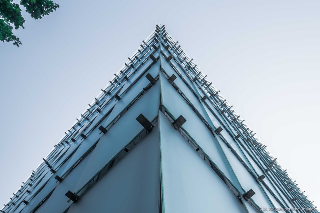 Ecke der Fassade Kunsthaus Bregenz mit rechteckigen schuppenartig vorgehängten Glasscheiben vor hellblauem Himmel - Architekturfotografie