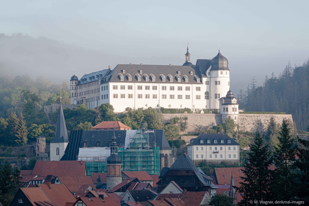 Schloss Stolberg ueber den Daechern des Ortes im Sonnenlicht vor Morgennebel im Hintergrund, Denkmalfotografie